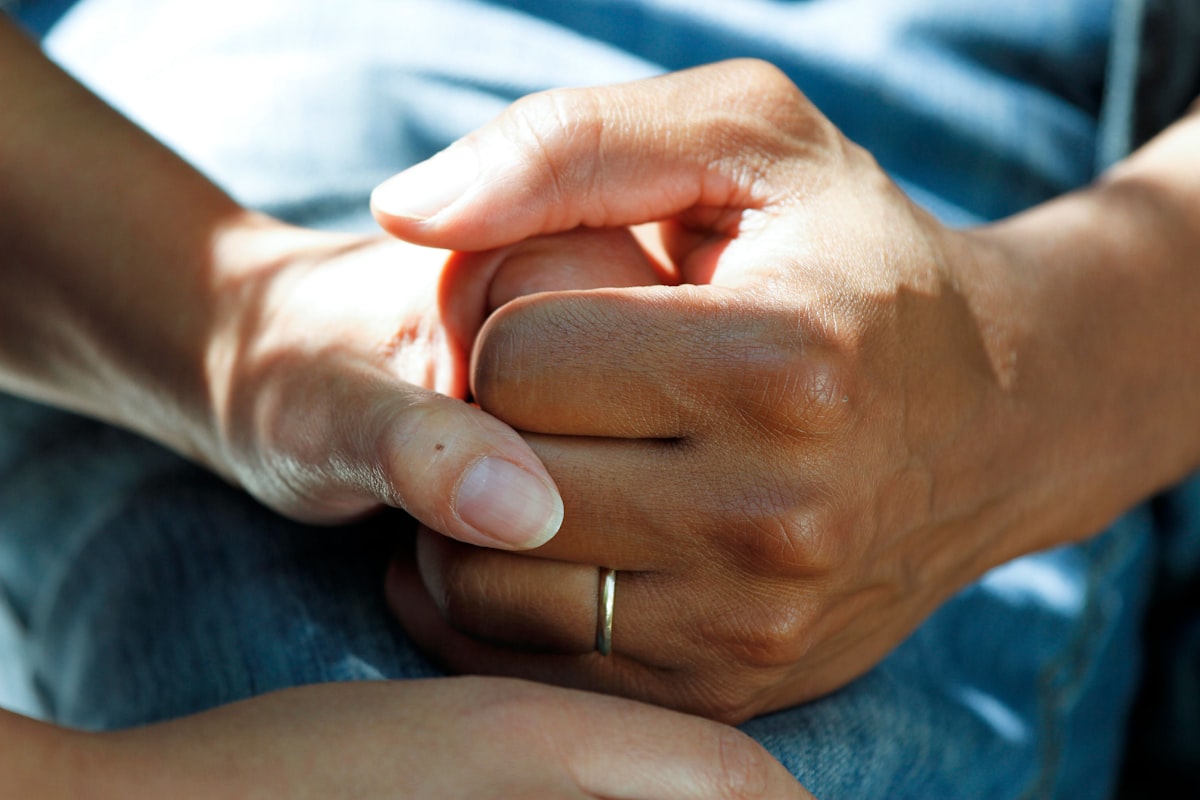 Compassionate wound care nurse holding patient hands during in-home visit